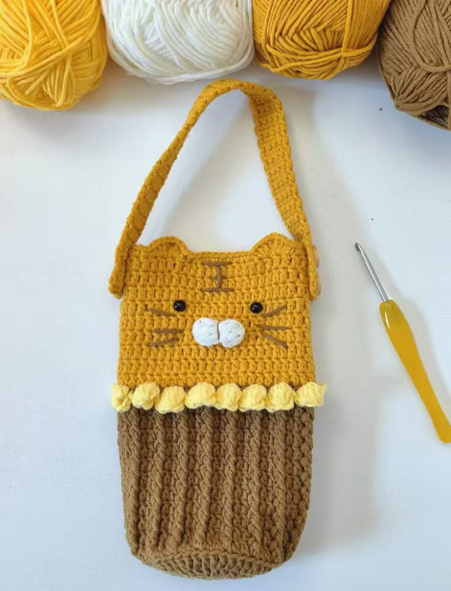 Crocheted cat-shaped pouch with yarn and a crochet hook on a white background