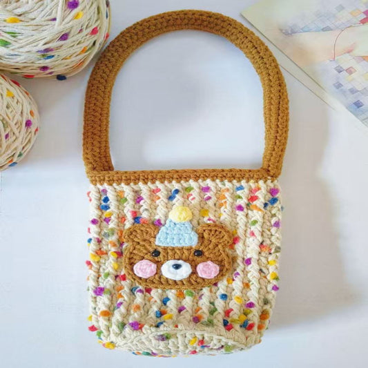 Crocheted bottle bag with colorful pom-pom details on a white background