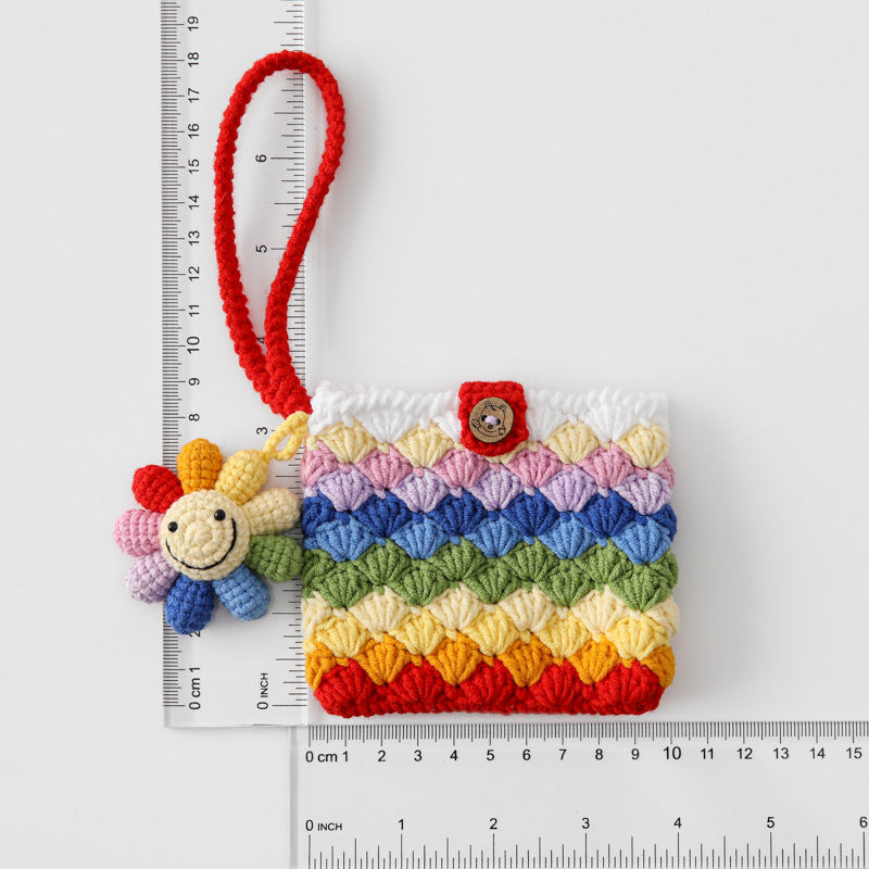 Colorful crocheted pouch with a bee charm next to a ruler for scale on a white background